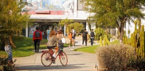 A Pitzer student bikes toward Mead Hall