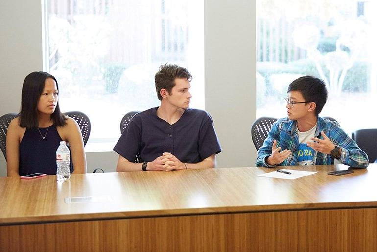 three students sit at a table during student senate